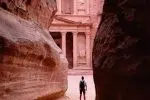 person walking on pathway between brown rock formation during daytime