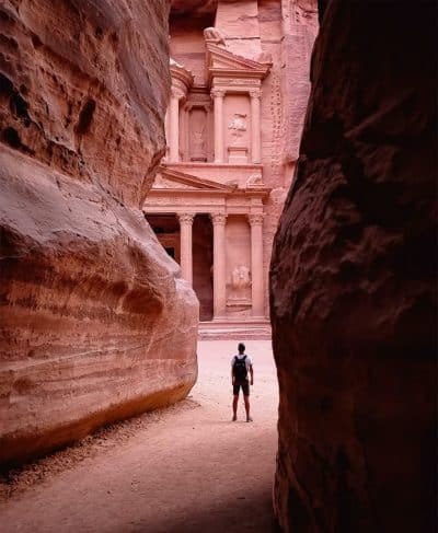 person walking on pathway between brown rock formation during daytime