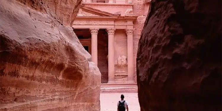 person walking on pathway between brown rock formation during daytime